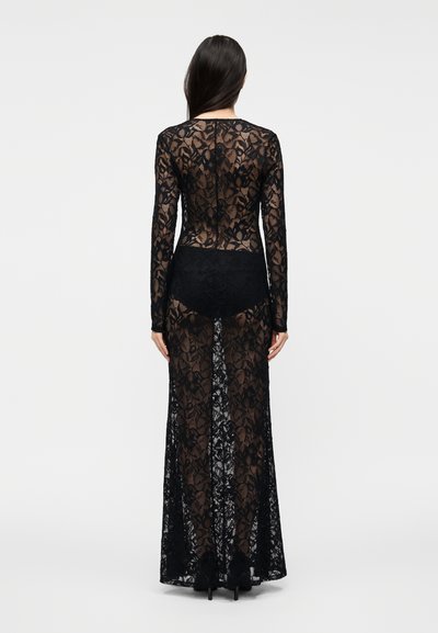 Juoda nėriniuota suknelė su ilgomis rankovėmis, prigludusiu liemeniu ir grindų ilgio sijonu, puošta gėlių raštais ir permatomu audiniu.