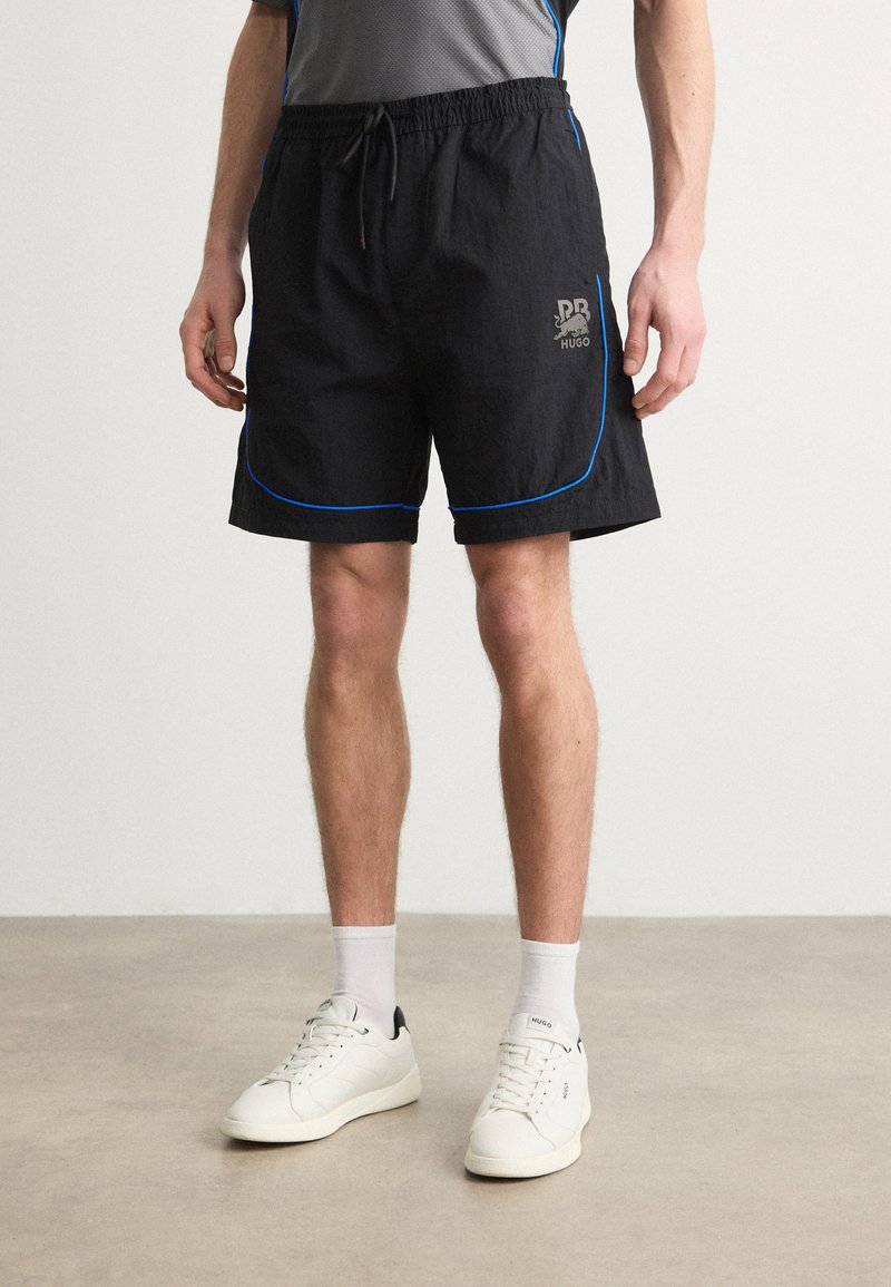 Pantalones cortos negros con ribetes azules y un logo. Hechos de material ligero, cuentan con una cinturilla elástica y bolsillos laterales.