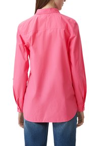 Lange mouwen, gekleed shirt in felroze, gemaakt van lichtgewicht stof. Voorzien van knoopmanchetten en een licht gebogen zoom aan de achterkant.