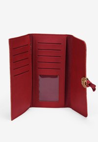 Cartera roja de tres pliegues abierta, mostrando múltiples ranuras para tarjetas y una ventana transparente para identificación, asegurada con un cierre de botón dorado y un lazo de tela roja.