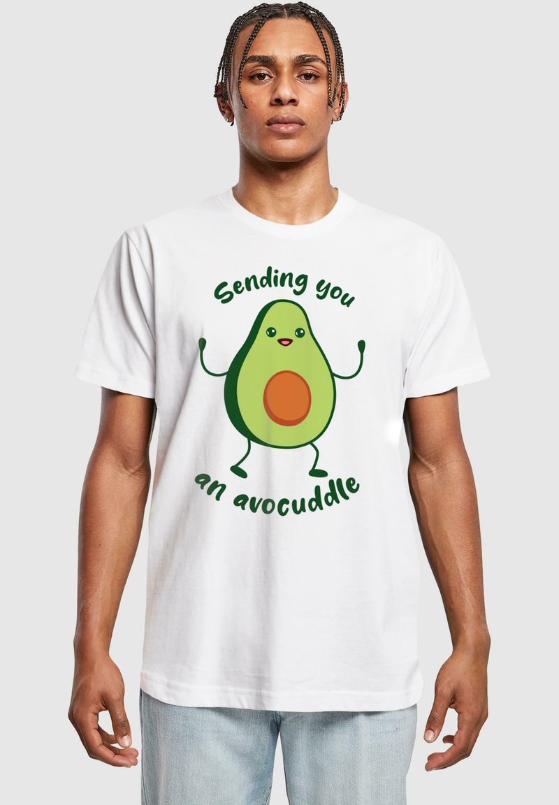Witte katoenen t-shirt met een cartoon avocado afbeelding met een bruine pit en groene accenten, de tekst luidt "Ik stuur je een avocuddle."