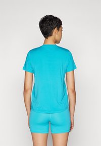 T-shirt de sport turquoise à manches courtes, texture lisse et col rond. Associé à un short assorti, les deux conçus pour le sport.