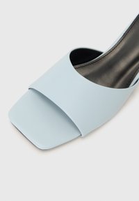 Lyseblå sandle med firkantet tådesign, laget av glatt syntetisk materiale, med en bred overdel og flat såle.