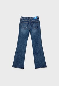 Flared blue denim jeans with a five-pocket design, featuring visible seams and a blue label on the waistband.
