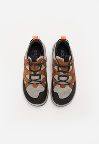 Smeđi i sivi tenisice od mrežastih i antilop materijala, s crnim gumenim potplatima, plavim akcentima i narančastim petnim nastavkom.