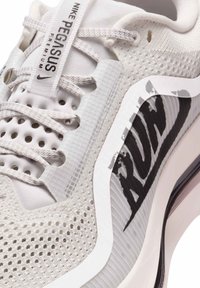 Hvide Nike Pegasus løbesko med mesh-overdel, teksturerede detaljer, grå branding og en polstret sål med mørke elementer.
