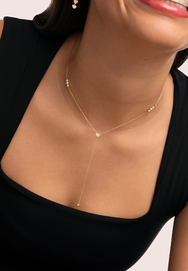 Collana d'oro con una delicata catena e tre piccoli accenti simili a diamanti, che creano una forma a Y che pende elegantemente.