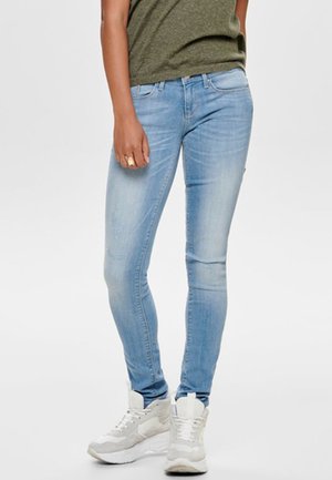 Light blue skinny jeans made of denim, featuring a classic five-pocket design. Worn with a dark green t-shirt and white sneakers.