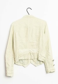 Veste en lin beige clair avec une finition texturée, dotée d'un col montant, d'un ourlet arrondi et de boutons décoratifs sur les manches.