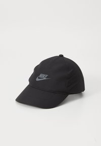 Căciulă de baseball Nike neagră cu bordină curbată și logo gri în față, plasată pe o suprafață albă.