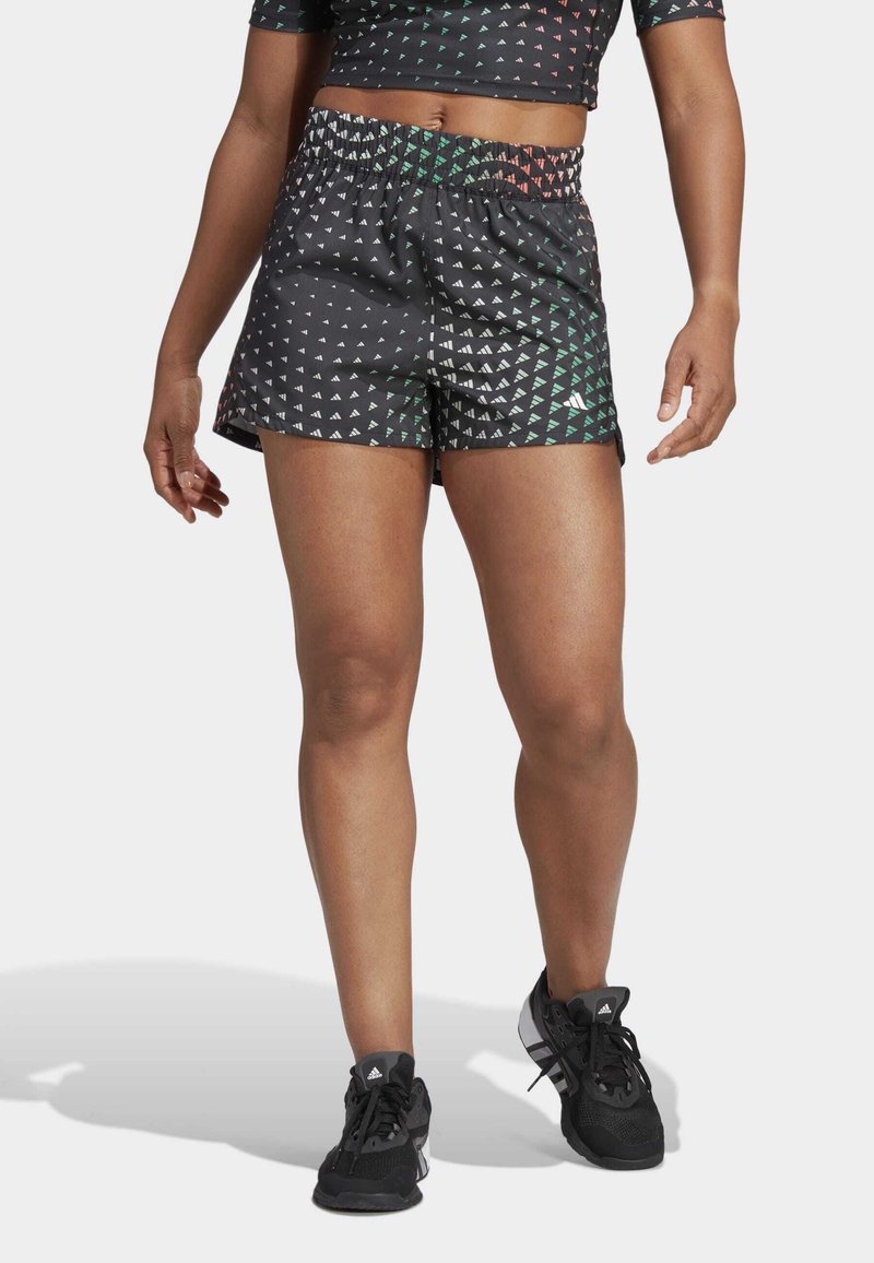 Svarta sportshorts med ett geometriskt mönster i gröna, röda och vita trianglar. Har en elastisk midjeband och sidospjäll.