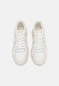 Hvite sneakers med en blanding av mesh og glatt skinn, med rund tå, tykk såle og subtile grå detaljer. Snøring er sentralt plassert.