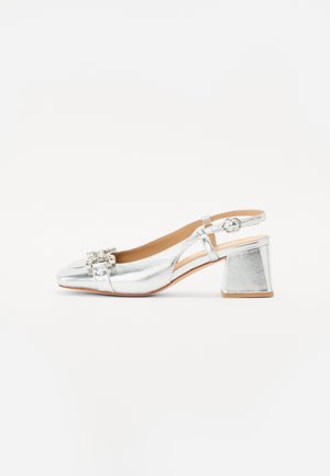 Sandal con tacco in argento con finitura metallica lucida, un tacco basso a blocco e decorazioni sulla punta. Presenta una tracolla regolabile.