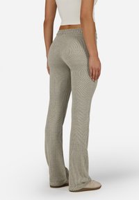 Svijetlosive hlače od rebraste pletenine s proširenim nogavicama i elastičnim pojasom. Tkanina je nježne teksture s diskretnim vertikalnim prugama.