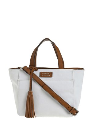 Sac à main en toile blanche avec poignées en cuir brun, bandoulière réglable, détail de pompon, et une petite étiquette de marque sur la poche avant.