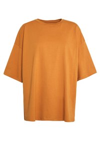Nadměrné tričko s krátkými rukávy z oranžové bavlněné látky. Jednoduchý kulatý výstřih, měkká textura a bez viditelných vzorů či detailů.