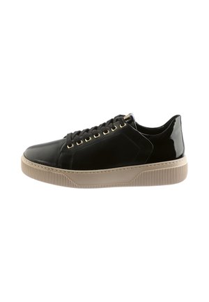 Sneakers basses noires avec semelle épaisse en caoutchouc beige, lacets noirs, œillets dorés et détail brillant au niveau du talon, présentés sur fond blanc.