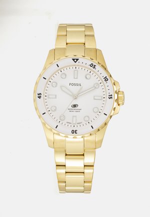 Orologio da polso in metallo dorato con quadrante bianco, indicatori delle ore argentati e marcature nere per i minuti. Presenta una cassa rotonda e un bracciale con maglie regolabili.