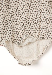 Ripp-Bodysuit in Creme mit einem Herzmuster-Design in Schwarz und Pink. Verfügt über Druckknopfverschlüsse am Boden und ein weiches Innenfutter.