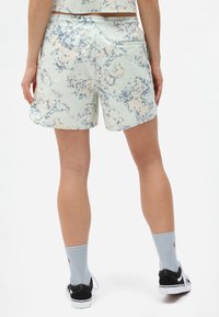 Světle modré kraťasy s mramorovým vzorem, elastickým pasem, bočními kapsami a elegantním designem, doplněné černými botami a šedými ponožkami.