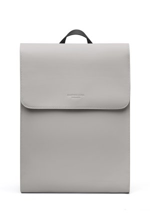 Minimalistische lichtgrijze rechthoekige rugzak met bovenvlak en klein zwart handvat, met subtiel reliëf merklogo op de voorklep.
