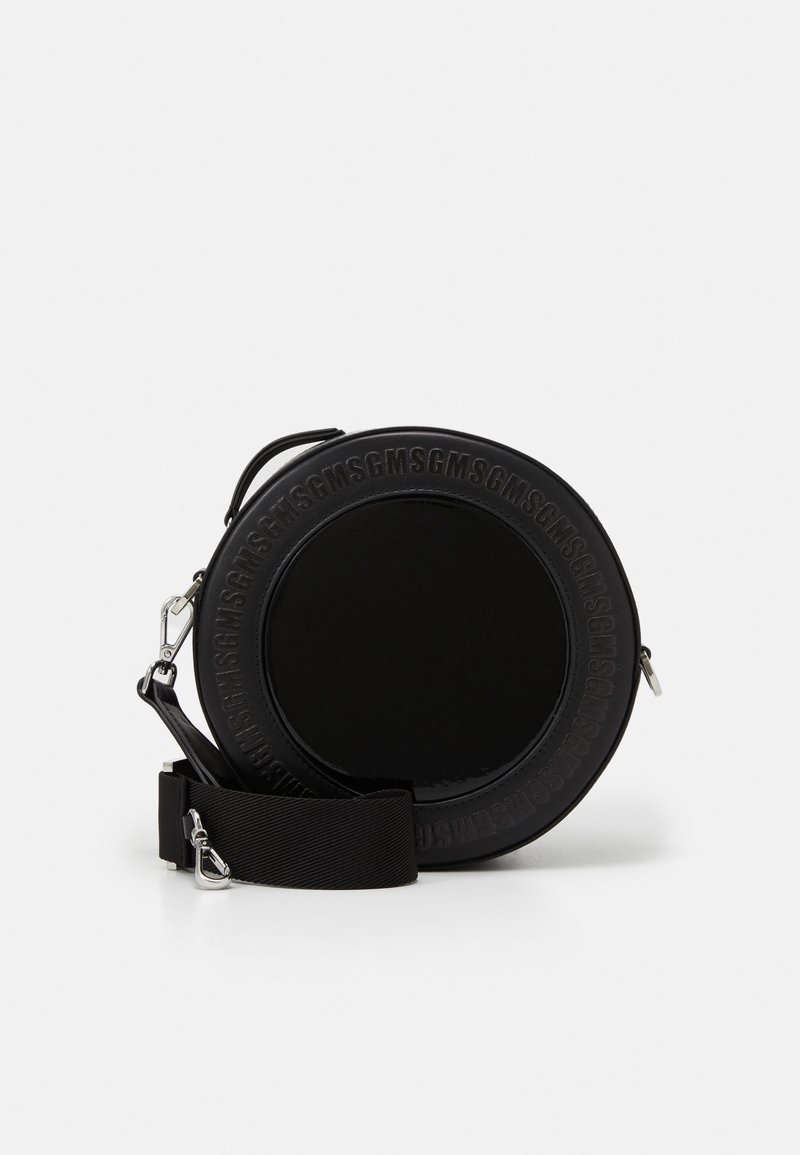 Sac bandoulière rond noir avec une finition brillante, texte en relief le long du bord, sangle ajustable et quincaillerie métallique. Texture lisse.