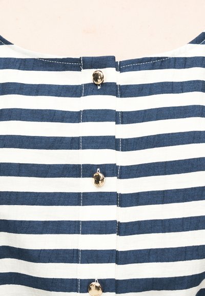 Ύφασμα με οριζόντιες ρίγες σε ναυτικό μπλε και λευκό, με μια κάθετη σειρά από τρία γυαλιστερά χρυσά κουμπιά.