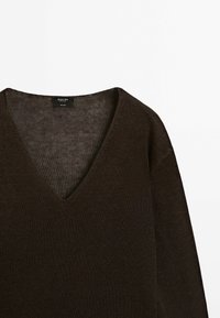 Pull en maille marron foncé à col en V, manches longues et étiquette à l'arrière du cou sur fond blanc uni.