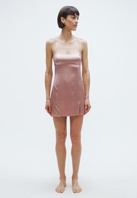 Satininė trumpa suknelė rožinės spalvos, su plonomis petnešėlėmis ir asimetrišku šoniniu įkirpimu, pasižyminti lygiu tekstūra ir minimalistiniu dizainu.