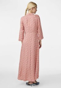 Robe longue rose avec un motif floral, manches longues, corsage ajusté et jupe fluide. Texture de tissu lisse. Encolure ronde simple.