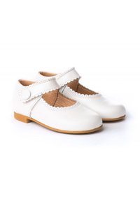 Zapatos de cuero blancos con puntera redondeada, ribete en forma de ondas y una sola correa con un botón redondo. Suela plana, diseñada para la comodidad.