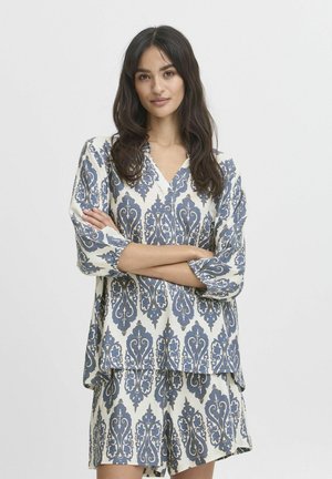 Ensemble imprimé composé de deux pièces avec un haut ample à col en V et un short. Motif damassé bleu et blanc sur un tissu texturé.