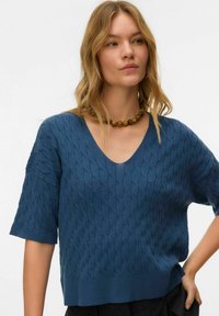 Plavi pleteni džemper s V-izrezom i kratkim rukavima, s teksturiranim uzorkom i rebrastim rubom. Ležerni kroj od mekanog materijala.