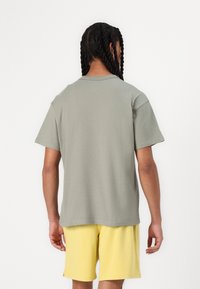Grijze katoenen t-shirt met korte mouwen en een losse pasvorm, gecombineerd met gele shorts. Eenvoudig ontwerp met een ronde hals en geen zichtbare patronen.