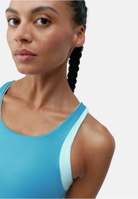 O bluză sport de un albastru deschis cu un design tip racerback, având un accent contrastant de un albastru pal pe bretelele umerilor. Material neted și elastic.