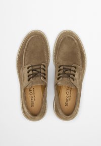 Braune Wildlederschuhe mit Schnürdesign, kontrastierenden Nähten und einer runden Zehenpartie. Das Innere verfügt über eine sandfarbene Einlegesohle mit Branding.