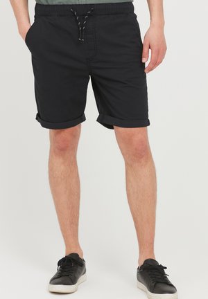Shorts noirs arrivant au genou, avec une taille élastique à cordon de serrage, des ourlets retroussés et des poches latérales, fabriqués en tissu léger.