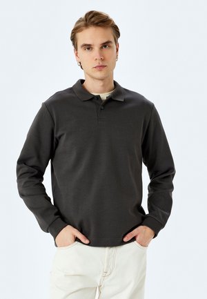 Mørkegrå langærmet polo skjorte med krave, featuring tre-knaps placket, lavet af blødt stof, parret med cremefarvede bukser.