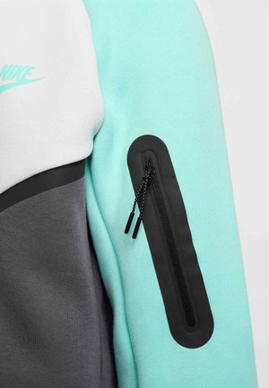 Nike sweatshirt med et design i hvid, teal og grå farveblok, med en lynlåslomme på ærmet og strukturerede stofdetaljer.