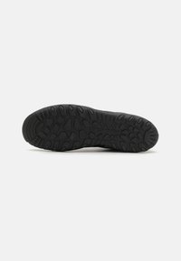 Suola di sneaker nera con un design testurizzato e patterned per una migliore aderenza, caratterizzata da una forma strutturata e realizzata in materiale gommoso durevole.