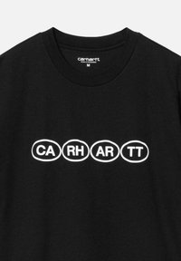 Camiseta de algodón negra con un gráfico blanco que presenta las letras "CA RH AR TT" en formas ovaladas, de manga corta y con cuello redondo.