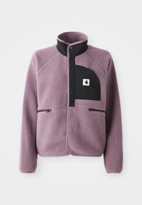 Chaqueta de forro polar morada con bolsillo abotonado negro en el pecho, cuello negro y dos bolsillos laterales con cremallera.