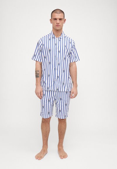 Cămașă cu mânecă scurtă, cu butoni, și pantaloni scurți asortați, de culoare albă cu dungi verticale albastre și desene animate. Material din bumbac, croială lejeră.