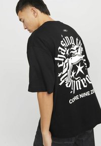 Sort oversized t-shirt lavet af bomuld. Har stort hvidt grafisk motiv med en hest og stjerner på bagsiden. Rund halsudskæring og korte ærmer.