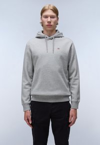 Felpa grigia con cappuccio e tasca frontale, dotata di un piccolo emblema. Polsini e orlo a costine, realizzata in un tessuto morbido e texture. Pantaloni neri.