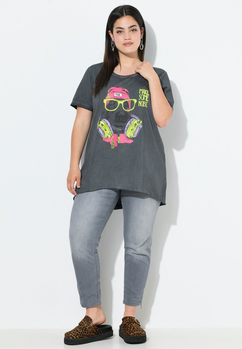 T-shirt oversized grise avec un graphisme coloré d'un cochon portant des écouteurs et des lunettes de soleil, associé à un jean gris clair et des sabots en imprimé léopard.