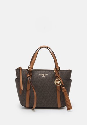 Michael Kors bruine monogram handtas met beige leren handvatten, afneembare schouderriem, gouden MK-logo bedel en voorkant met kwastdetail.