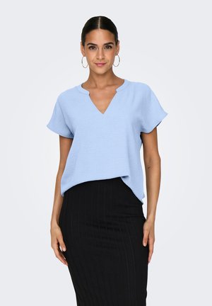 Jasnoniebieski top z krótkim rękawem i dekoltem w serek, wykonany z teksturowanej tkaniny, noszony na czarnej, prążkowanej ołówkowej spódnicy. Prosty, luźny krój.