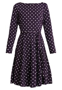 Lila knälång klänning med vita prickar, lång ärm, båtformad halsringning och ett matchande tygbälte knutet i midjan.