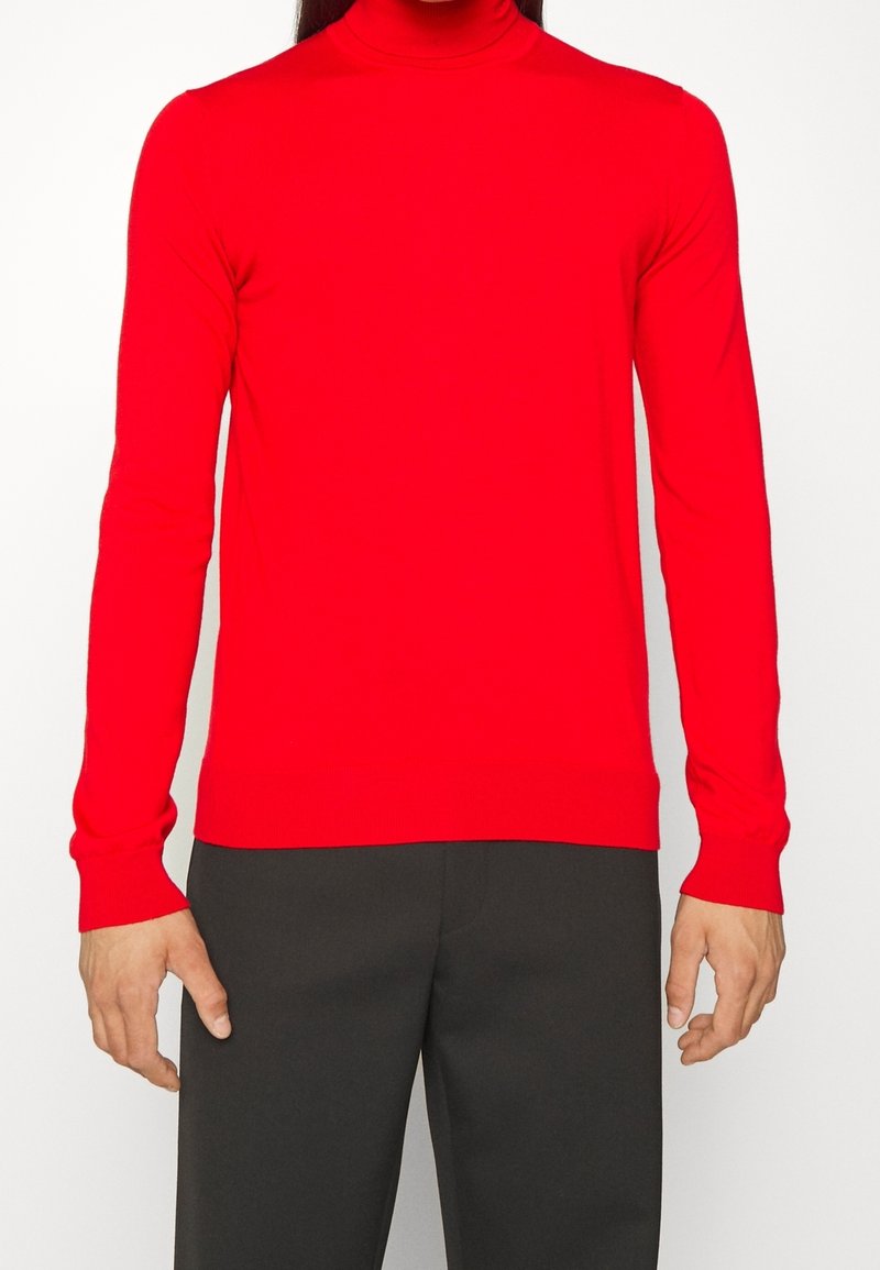 Pull à col roulé rouge, coupe ajustée, en tissu tricoté lisse, avec manches longues et poignets et ourlet côtelés.